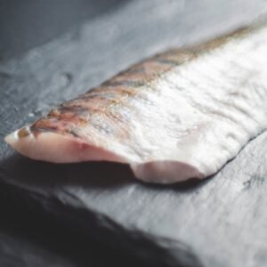 Close-up of a fresh salmon fillet placed on a dark slate surface, capturing its natural texture.